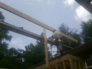 Carpenter setting a ridge beam over a new addition frame — Ice Dam Removal by Roofing Brothers in Alex