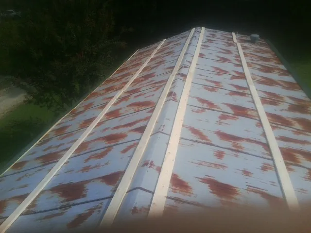 Rusted metal roof panels with new wood purlins before replacement — Storm Damage Roof Repair in Alex by Roofing Brothers