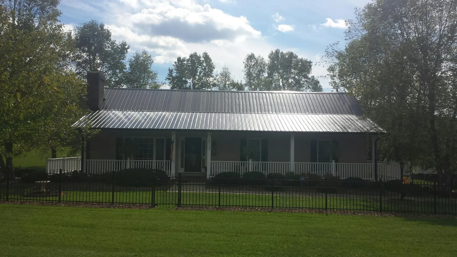 Gray metal roof on a brick ranch with a full width front porch — Gutter Guard Installation work by our crew in Alex